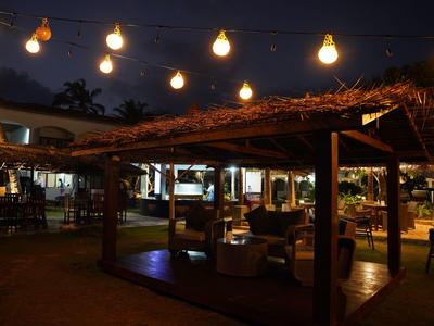 Gemütlicher Außenbereich eines Hotels bei Nacht mit Lichterketten und Sitzgelegenheiten unter einem Pavillon.