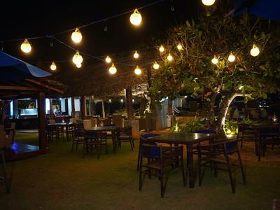 Beleuchteter Außenbereich eines Hotels mit hängenden Lampen und Gartenmöbeln in der Nacht.
