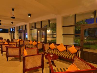 Gemütlicher Hotel-Loungeraum mit Holzmöbeln und orangefarbenen Kissen bei Abendlicht.