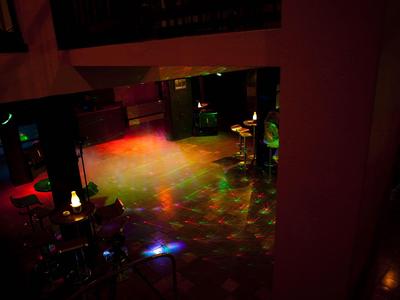 Leerer Tanzboden mit bunten Lichtprojektionen in einer dunklen Bar oder einem Club.