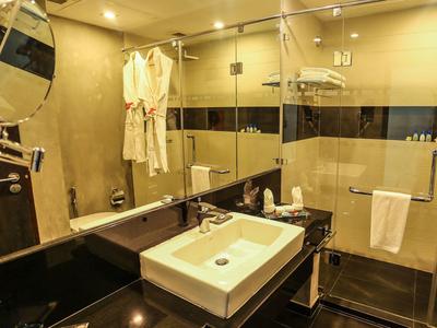 Modern hotel bathroom with glass shower, white towels, and bathrobes.