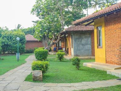 Bungalow complex with well-kept lawn, walkway, and trees under blue sky.