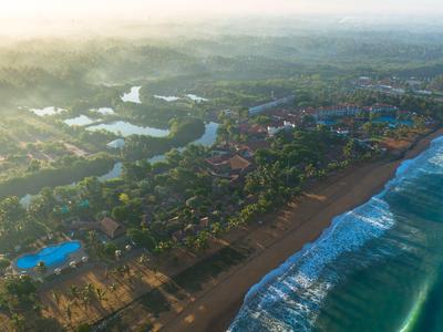Aerial view of a coastal town with beach, waves, and hotels in the early morning.