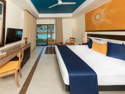 Modern hotel room with large bed, desk, and view of balcony and sea.