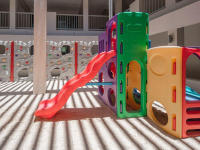 Colorful children's playground with slide in a bright courtyard with shadow lines.