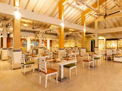 Bright restaurant with wooden beams, tables, and chairs, warmly lit and spacious.