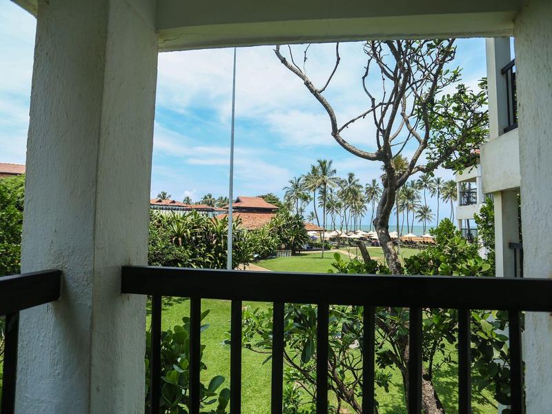 Balcony view of palm trees and green lawns under a blue sky.