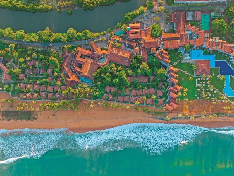 Aerial view of a resort complex with multiple pools, green areas, and beach access.