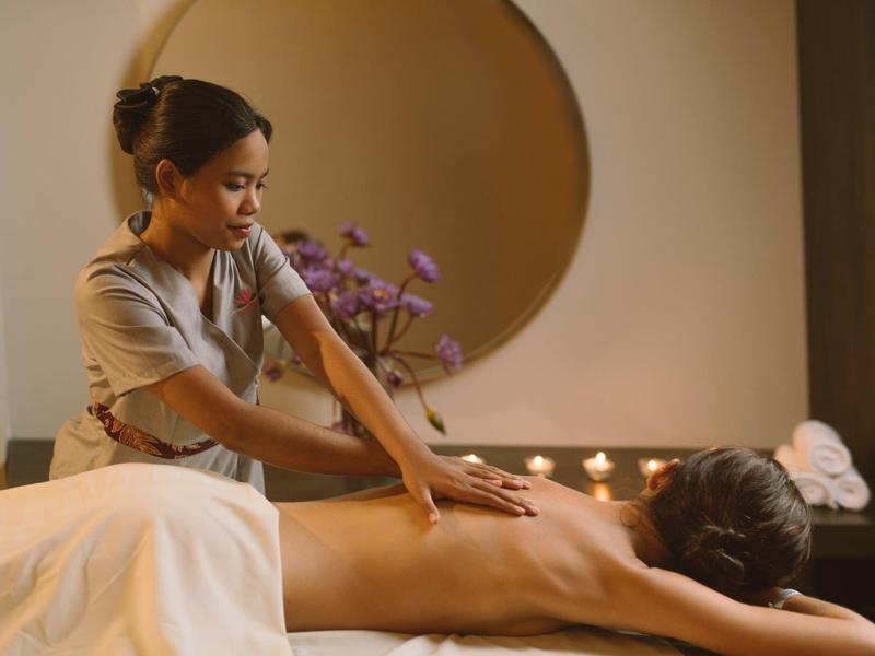 A woman receives a back massage from a masseuse in a calm room.
