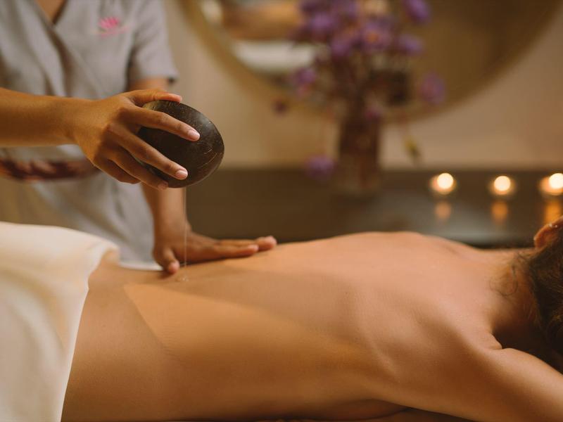 Person receiving a hot stone massage on the back in a relaxing spa setting.