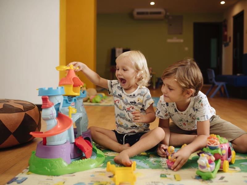 Two children playing together with a colorful toy in the living room.