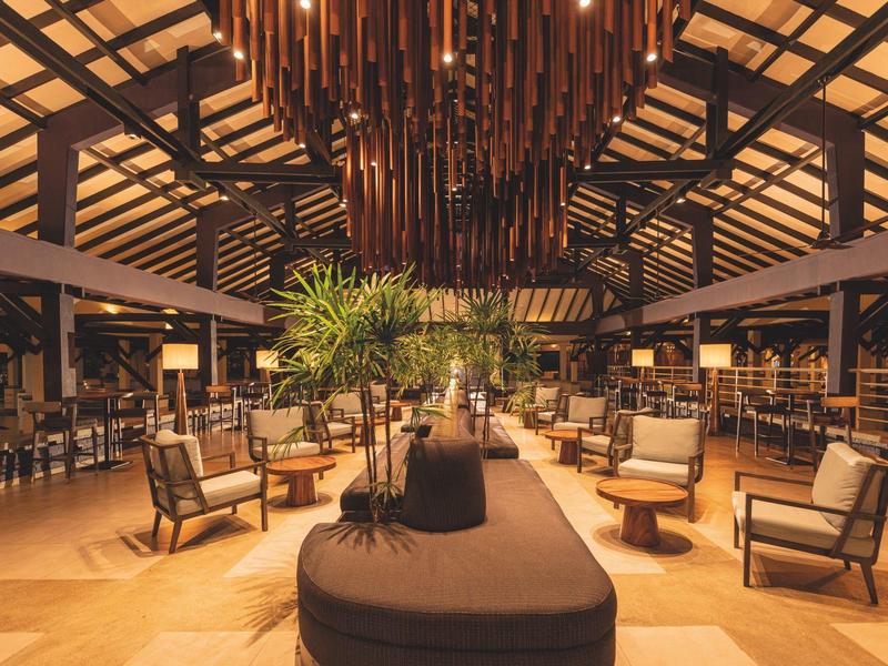 Spacious hotel lobby with seating areas, modern lighting, and tropical decor.