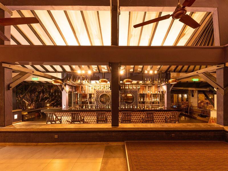 Cozy bar with wooden beams and ceiling fans, warmly lit in the evening.
