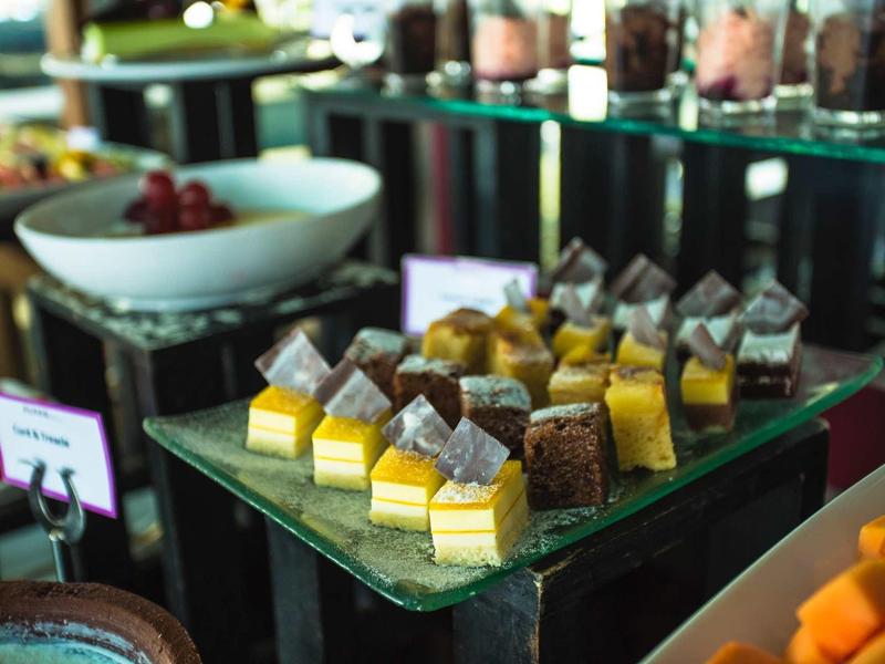 Verschillende kleine stukjes cake op een glazen schaal in een buffetgedeelte.