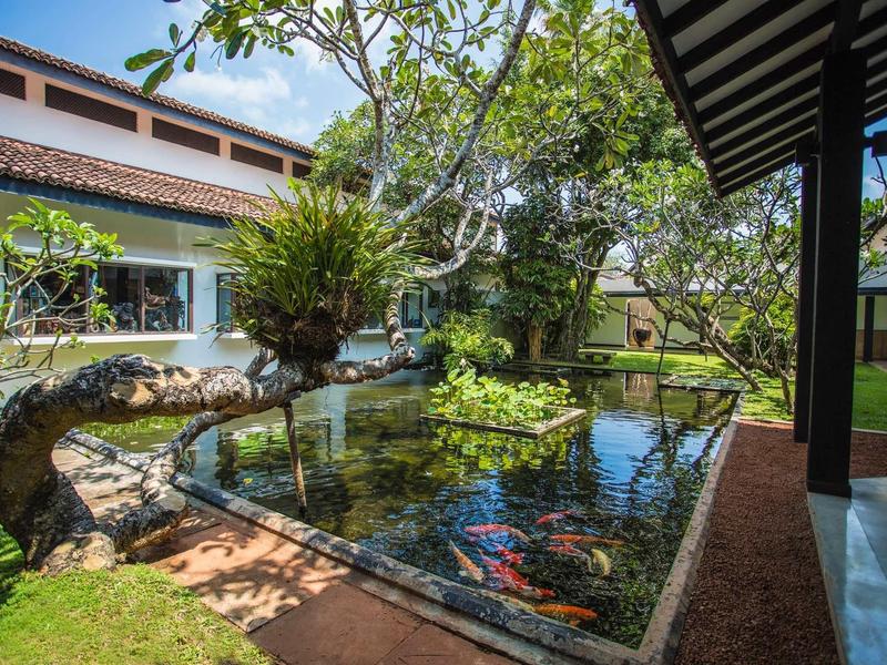 Rustige plek met vijver, beplante nissen en overdekte paden in een hotel tuin.