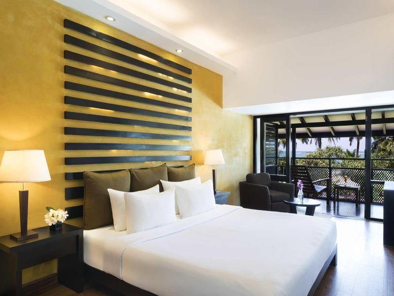 Moderne hotelkamer met groot tweepersoonsbed en raam met uitzicht op terras en tuin.