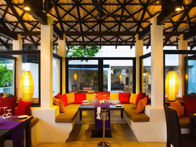 Goed verlichte hotellounge met kleurrijke kussens en moderne lampen.