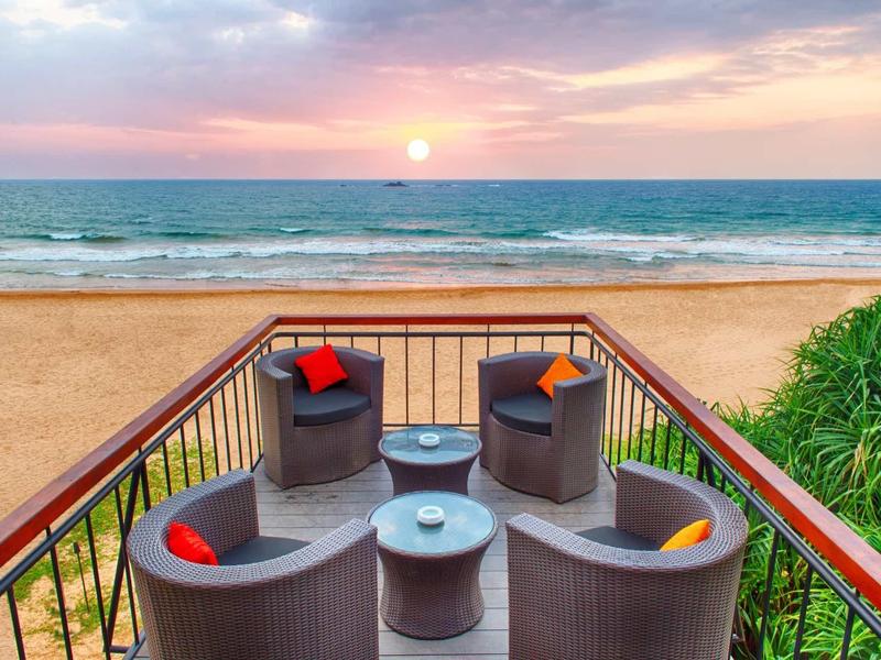 Terras met zithoek met uitzicht op het strand en de zee bij zonsondergang.