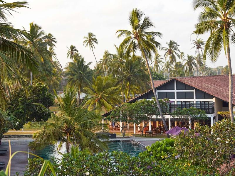 Resort hotel met zwembad en veel palmbomen in een tropische omgeving