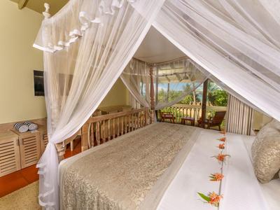Luxuriöses Hotelzimmer mit Himmelbett, weißen Vorhängen und Blick auf eine grüne Landschaft.