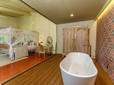Hotelzimmer mit freistehender Badewanne, Holzboden und traditionellem Baldachinbett.