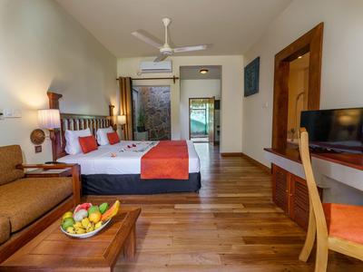 Modern eingerichtetes Hotelzimmer mit Doppelbett, Sofa, Holzboden und Flachbildfernseher.