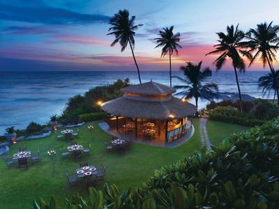 Bar de plage en soirée avec palmiers et tables dressées dans un cadre tropical.
