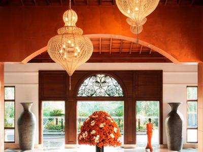 Entrance hall with wooden ceiling, large chandeliers, and flower arrangement on table.