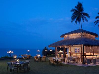 Cozy beach bar with tables under palm trees at night by the sea.