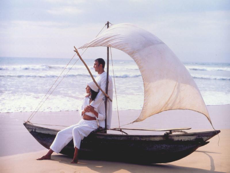 Un couple se détend sur un petit voilier sur la plage par temps calme.