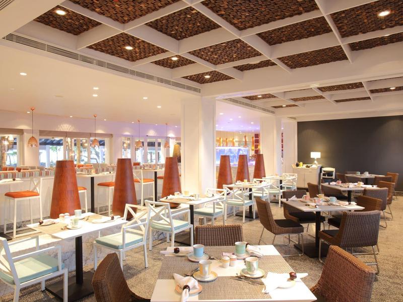 Restaurant moderne et lumineux avec tables blanches, chaises marron et plafond décoratif.