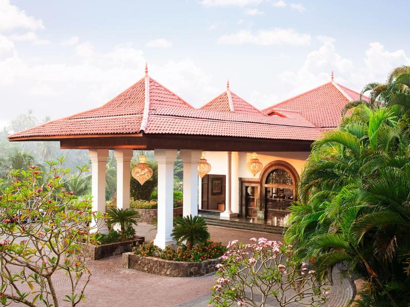 Hôtel avec toit rouge et véranda ouverte entourée de végétation verte.