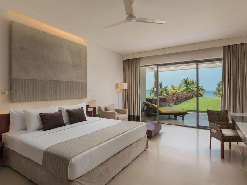 Moderne hotelkamer met groot bed, gezellige zitplaatsen en een terras met hangmat en uitzicht op de tuin.