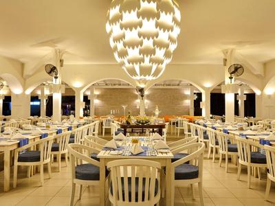 Großer, heller Speisesaal mit weißen Holzstühlen, blauen Polstern und stilvollen Kronleuchtern.