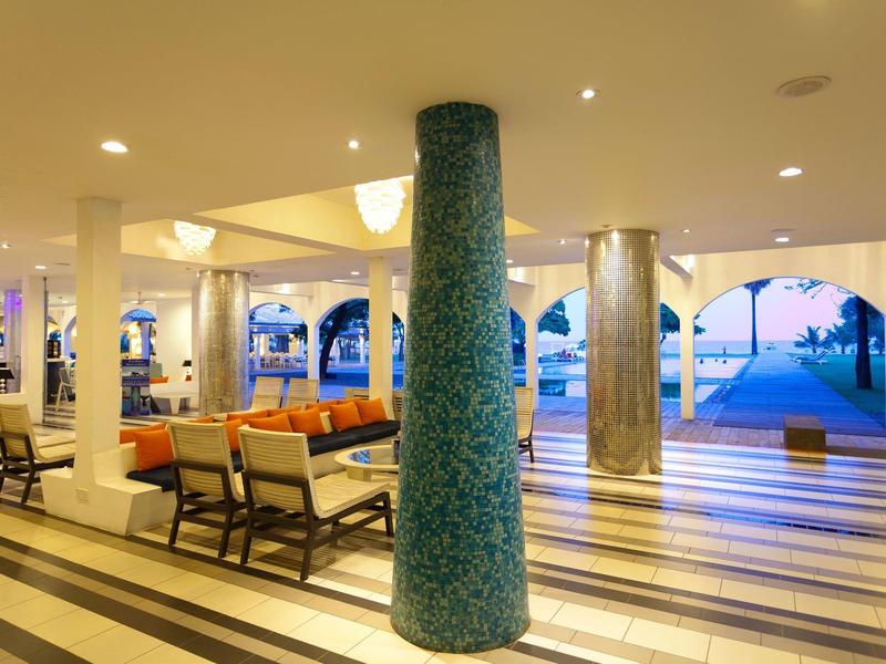 Großer, moderner Innenbereich mit Säulen, Sitzbereichen und Blick auf den blauen Himmel außen.