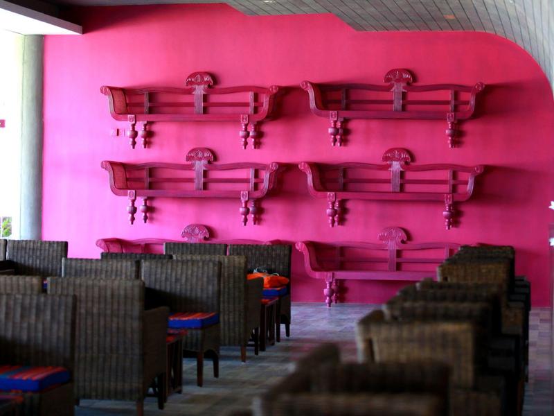 Restaurant mit pinkfarbener Wand, dekoriert mit mehreren alten Gewehren aus Holz.