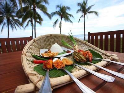Comida tropical de hotel con arroz y camarones en bandeja de bambú, palmeras al fondo.