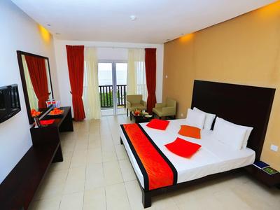 Habitación de hotel moderna con cama doble, ropa de cama roja y negra y vista al balcón.