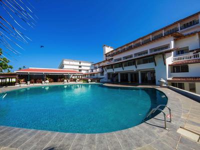 Gran piscina de hotel con agua azul clara y terraza circundante bajo cielo despejado.
