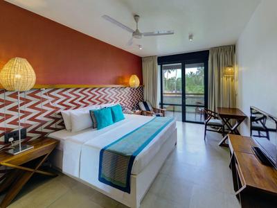 Nowoczesny pokój hotelowy z dużym łóżkiem, kolorowymi akcentami i widokiem na balkon.