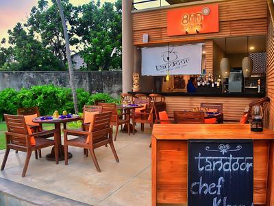 Przytulny ogródek restauracyjny z drewnianymi meblami i tablicą z ofertą dnia.