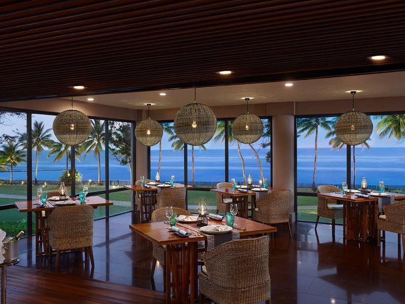 Restauracja z panoramicznymi oknami i widokiem na ocean oraz palmy