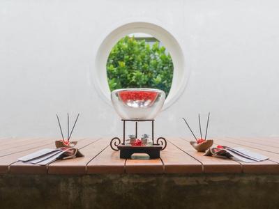 Twee gedekte houten tafels met een decoratieve karaf en uitzicht op een boom door een rond raam.