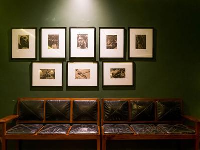 Zwei dunkelbraune Ledersofas vor einer grünen Wand mit acht gerahmten Bildern darüber.