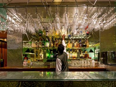 Barkeeper rangschikt glazen bij een goed gevulde hotelbar met spiegel- en glasaccenten.