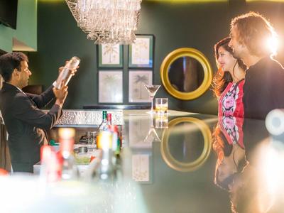 Barkeeper schudt cocktail voor twee gasten bij een stijlvolle hotelbar.