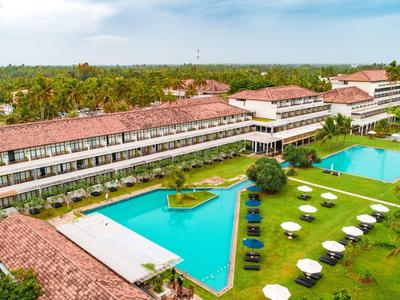 Grande resort con due piscine blu, sdraio, ombrelloni e ampi prati verdi.