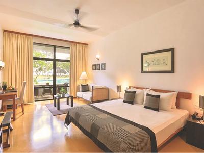 Modern hotelkamer met groot bed, balkon en plafondventilator.