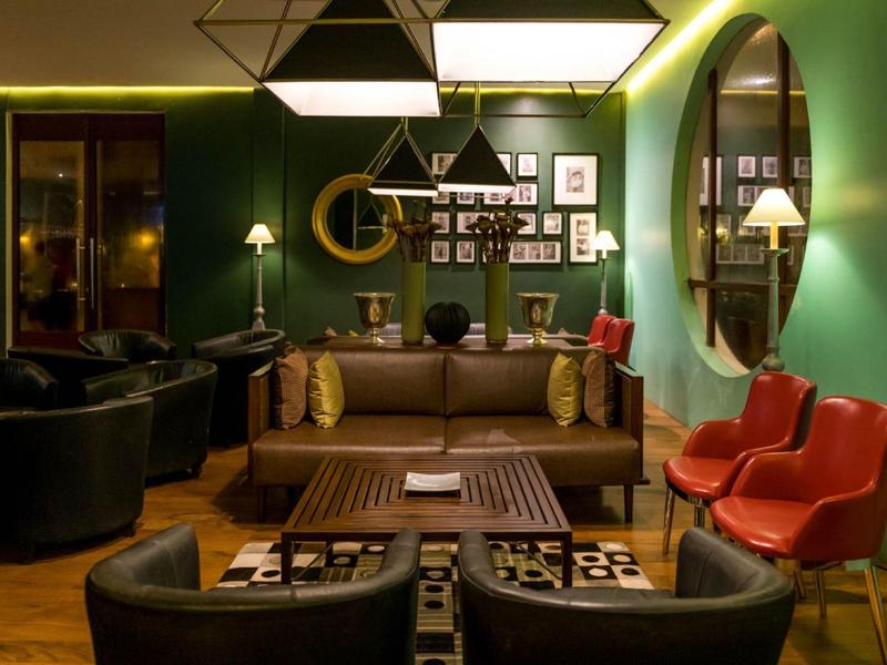 Gezellige hotel lounge met donkere muren, lederen fauteuils en warme verlichting.