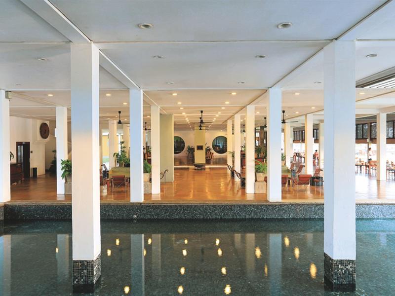 Interieur van een hotel met verwarmd zwembad, witte zuilen, heldere plafond en houten vloer.